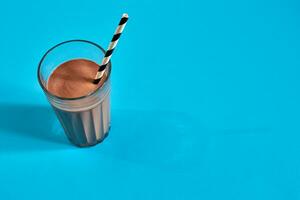 Glass of chocolate milk on blue background photo