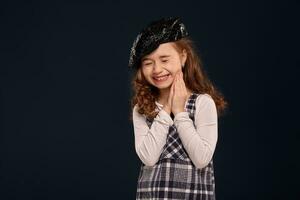 Stylish brunette kid is posing in studio on a black background. Children's fashion. photo