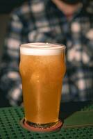 Closeup of frothy wheat unfiltered beer in glass on bar counter photo