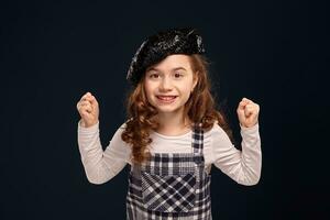 Stylish brunette kid is posing in studio on a black background. Children's fashion. photo