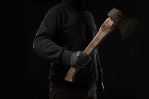 A man in gloves holds an ax in his hands against a black background photo