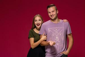 Young nice couple posing in the studio, express emotions and gestures, smiling, on a burgundy background photo