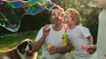 Dad and son blow bubbles on the lawn near the house. video