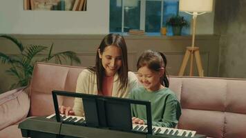 Asian mom and daughter learn to play the piano using a digital tablet. video