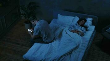 insatisfecho casado Pareja utilizar teléfono inteligente a noche mientras durmiendo. video