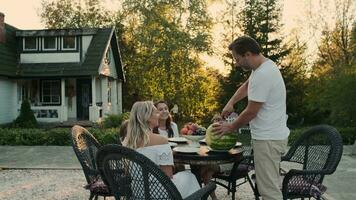 caucasiano família jantar com frutas dentro natureza perto a casa. video