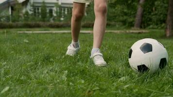 jambes de une enfant qui pièces avec une football balle. video