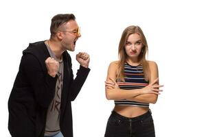 Young emotional man and woman quarrel. Man screaming at the woman waving her arms. photo