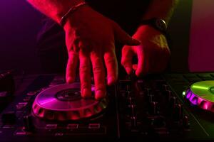 Dj mixing on turntables with color light effects. Soft focus on hand. Close-up. photo
