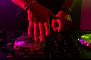 Dj mixing on turntables with color light effects. Soft focus on hand. Close-up. photo