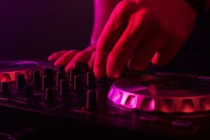 Dj mixing on turntables with color light effects. Soft focus on hand. Close-up. photo