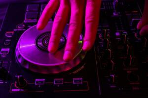 Dj mixing on turntables with color light effects. Soft focus on hand. Close-up. photo