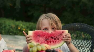 ein Kind Theaterstücke mit ein Stück von Wassermelone Sitzung beim das Tisch. video