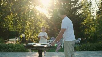 Father and son are preparing a table for dinner on the street near the house. video