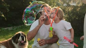 Dad and son blow bubbles on the lawn near the house. video