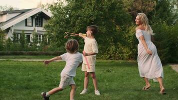 maman et deux fils jouer sur le pelouse près le maison. video