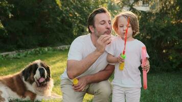 Dad and son blow bubbles on the lawn near the house. video