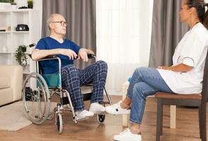 Patient and doctor talking in cozy apartment. Disabled disability old person with medical worker in nursing care home assistance, healthcare and medicine service. photo