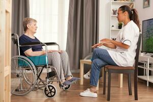 Nurse checking on retired handicapped old woman. Disabled handicapped old person recovering professional help nurse, nursing retirement home treatment and rehabilitation photo