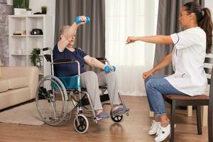 Senior woman in wheelchair doing physical rehabilitation with with doctor. Disabled handicapped old person recovering professional help nurse, nursing retirement home treatment and rehabilitation photo