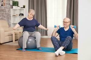 60 years old couple exercising together at home sitting on yoga mat. Old person healthy lifestyle exercise at home, workout and training, sport activity at home on yoga mat. photo