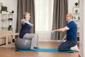 Cheerful senior couple training together on yoga mat. Old person healthy lifestyle exercise at home, workout and training, sport activity at home. photo