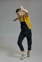 Full-length portrait of a funny guy dancing in studio on a gray background. photo