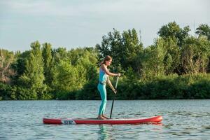 Confident woman standing with a paddle on the surfboard, SUP photo