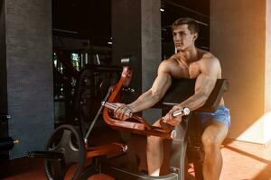 Tense muscles of hands under load. Man doing exercise for biceps in the gym. photo