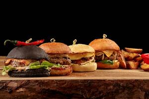 Set of burgers with meat, cheese, tomatoes, mayonnaise on wooden table, black background. Space for text. photo
