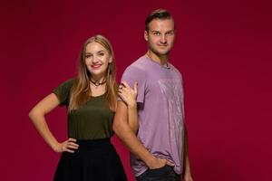 Young nice couple posing in the studio, express emotions and gestures, smiling, on a burgundy background photo