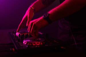 Dj mixing on turntables with color light effects. Soft focus on hand. Close-up. photo