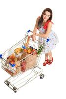 High angle view of girl smiling at camera while pushing a shopping cart full with groceries isolated on white background. photo