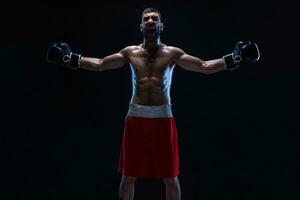 oriental Boxer celebrando su victoria con elevado brazos en negro guantes. foto