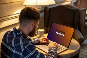 recortado imagen de un joven hombre trabajando en su ordenador portátil en un café comercio, joven masculino estudiante entra un contraseña en computadora sentado a de madera mesa. foto