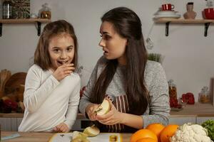 Mother and her daughter are doing a fruit cutting and having fun at the kitchen. photo