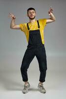 Full-length portrait of a funny guy dancing in studio on a gray background. photo