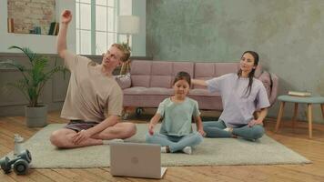 The family is engaged in fitness yoga at home using online technology. video