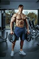 Male bodybuilder, fitness model trains in the gym photo