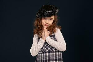 Stylish brunette kid is posing in studio on a black background. Children's fashion. photo