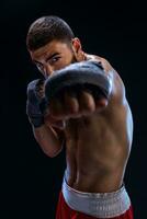 The boxer is ready to deal a powerful blow. Photo of muscular man with strong hands and clenched fists in blue stripes on black background.