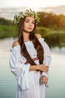 Woman in white dress in the water. Art Woman with wreath on her head in river. Wreath on her head, Slavic traditions and paganism photo