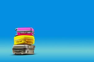 Three multicolored suitcases are lying on top of each other against a blue background. Collage. Copy space, close-up. photo