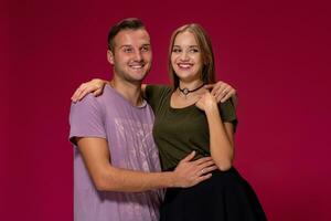 Young nice couple posing in the studio, express emotions and gestures, smiling, on a burgundy background photo