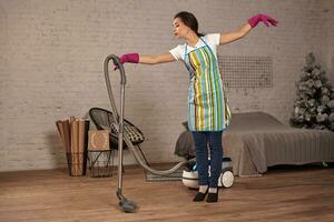 Happy woman cleaning home,dancing with vacuum cleaner and having fun, copy space. photo