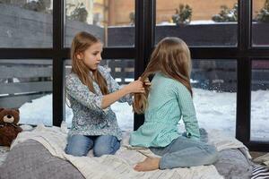 The image of two cute little sisters sitting on windowsill in peace and quiet photo
