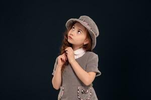 estudio Disparo de un encantador pequeño niño con un largo, Rizado pelo posando en un negro antecedentes. foto