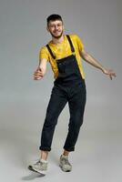 Full-length portrait of a funny guy dancing in studio on a gray background. photo