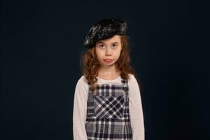 Stylish brunette kid is posing in studio on a black background. Children's fashion. photo