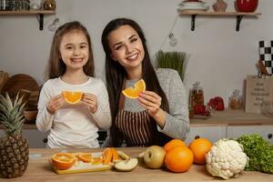 Mother and her daughter are doing a fruit cutting and having fun at the kitchen. photo